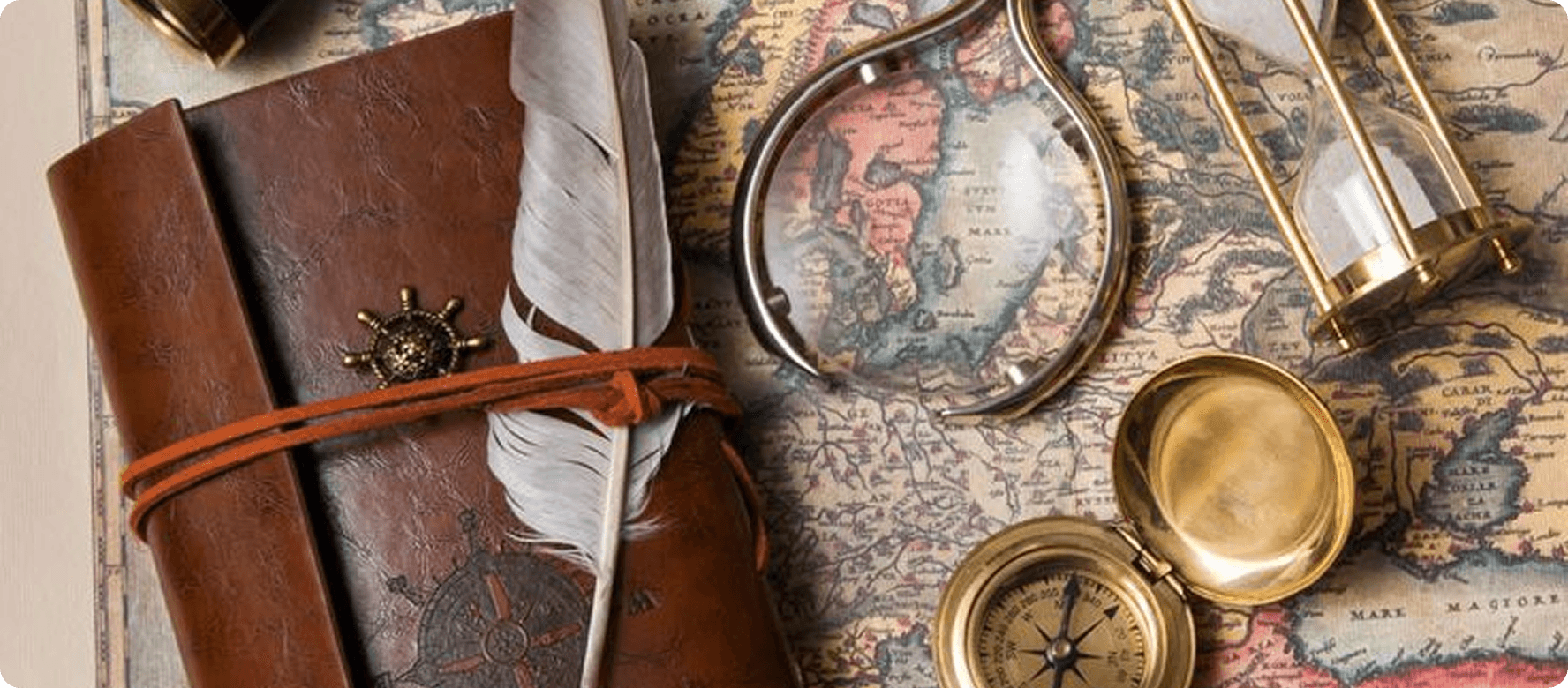 A journal, compass and hourglass laid over an old map